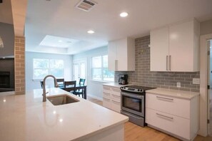 Una cocina moderna con armarios blancos, horno empotrado y una isla grande con lavamanos.