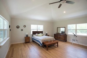 A spacious bedroom with a large bed, a desk, a dresser, and a ceiling fan. - 2 Large Bedrooms | Private | Downtown (Manchaca)