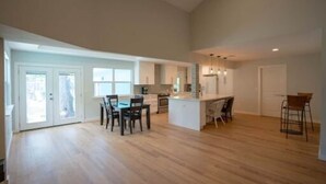 A spacious kitchen with an island, a dining area with chairs, and a large open space with a wooden floor.