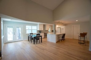 A spacious kitchen with an island, a dining area with chairs, and a large open space with a wooden floor. - 2 Large Bedrooms | Private | Downtown (Manchaca)