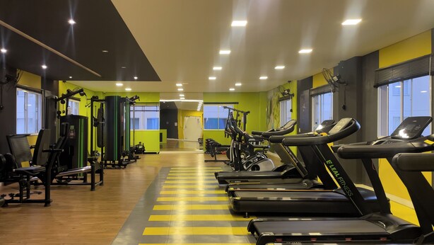 Een fitnessruimte met loopbanden, krachtapparaten en een spiegelwand.