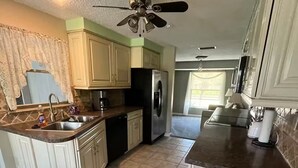 Une cuisine dotée d’un îlot central, d’un réfrigérateur et d’un ventilateur de plafond.