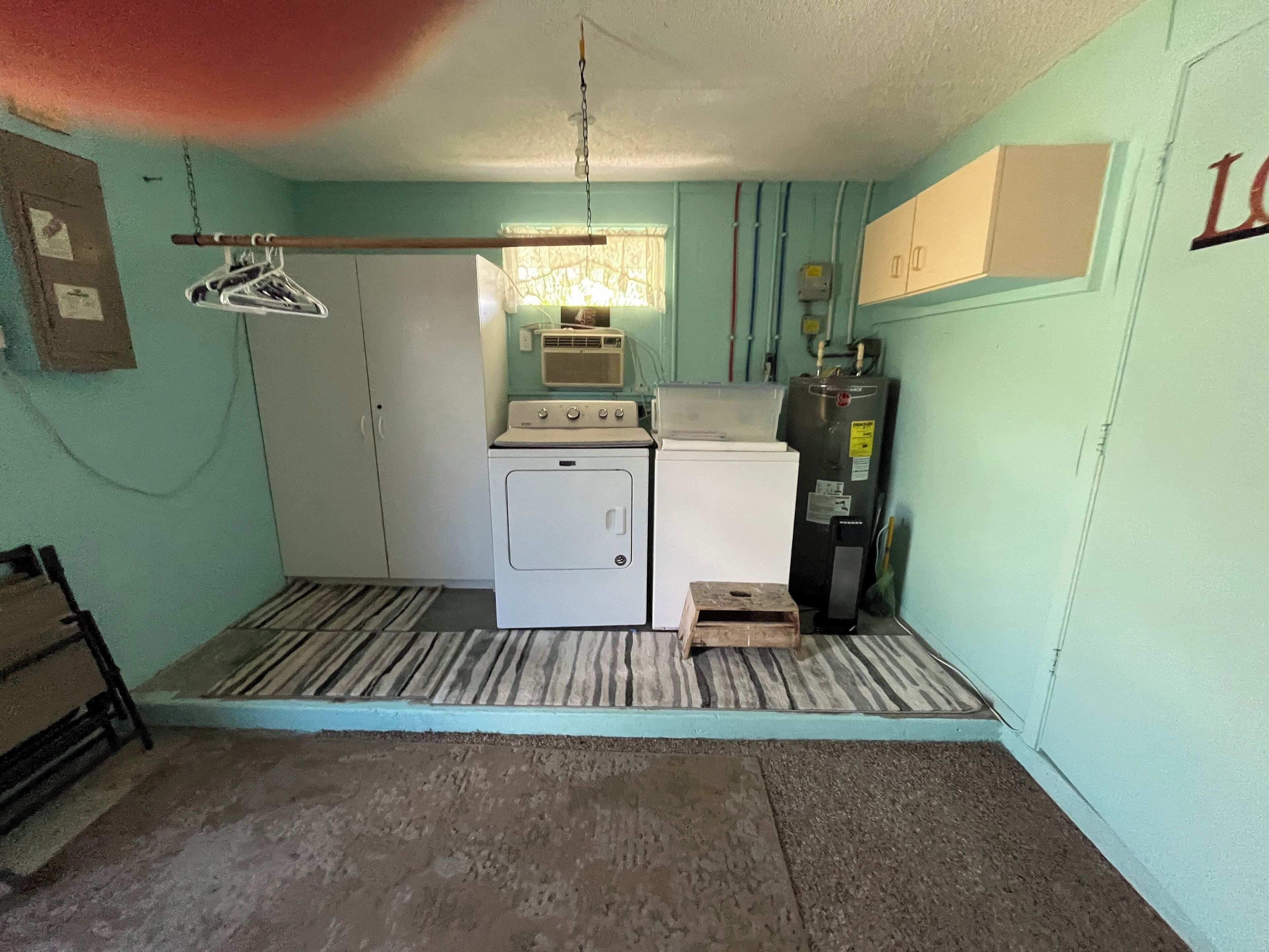 A compact laundry room with a washing machine, dryer, and a water heater.