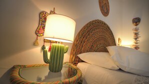 Ein Bett mit einem gestreiften Kopfkissen und einer Lampe mit Kakteenfuß.