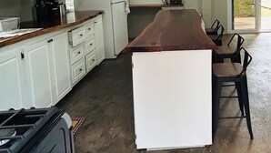 A spacious kitchen with white cabinets, a central island, and a large window.