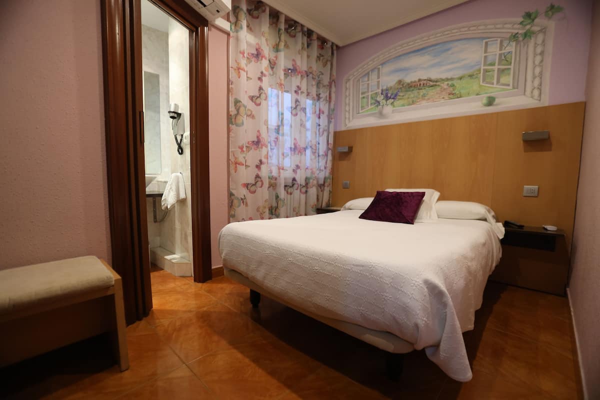 Ein Schlafzimmer mit einem Bett, einer Bank, einer Dusche und einem Wandgemälde.
