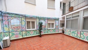 A courtyard with tiled flooring, a potted plant, and a decorative tiled wall. - Hostal Goya Suites (Salamanca)