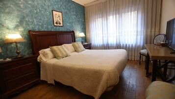 Une chambre d’hôtel avec un grand lit, des tables de chevet en bois, un bureau et une chaise.