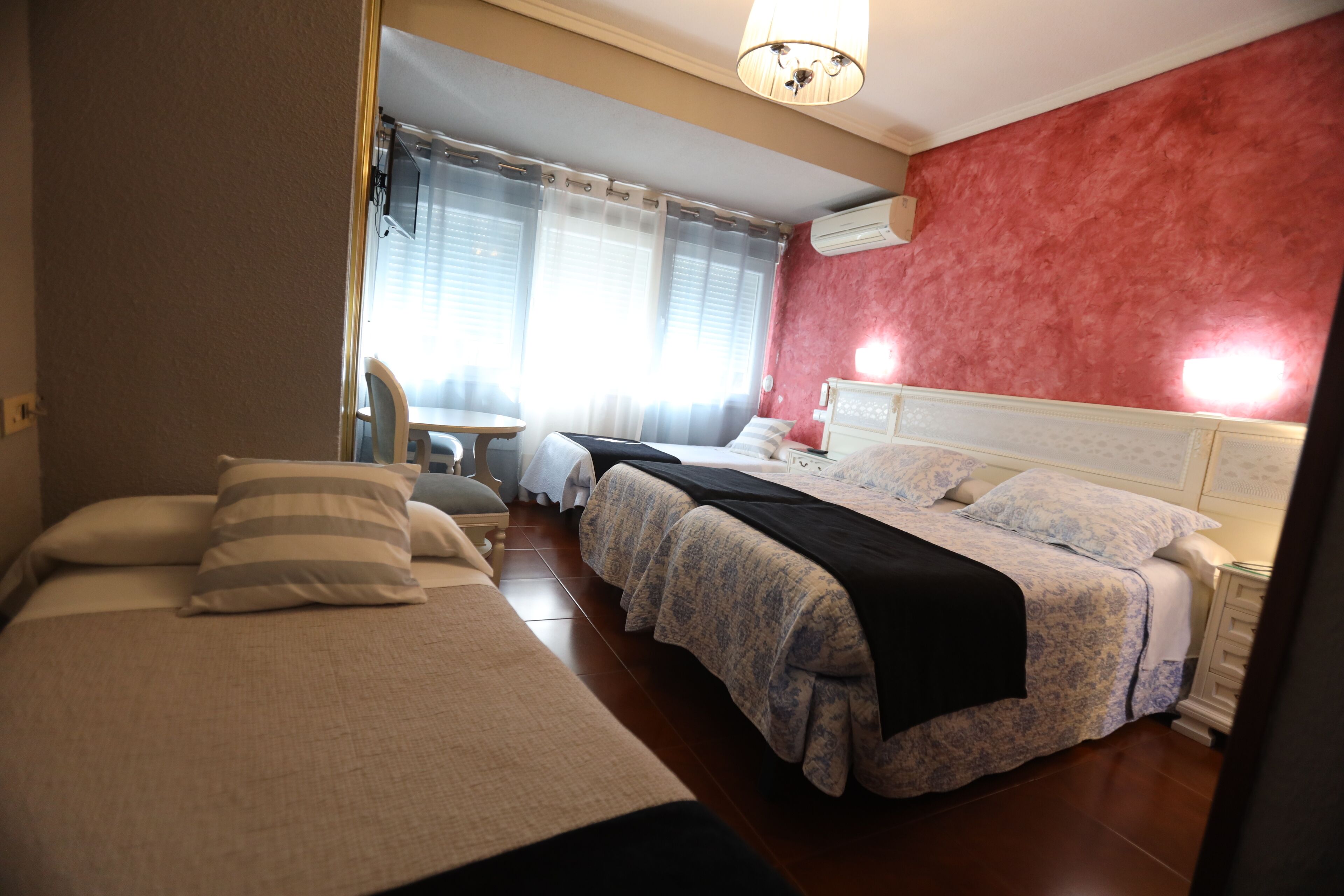 A hotel room with two beds, a small table, and a chair.