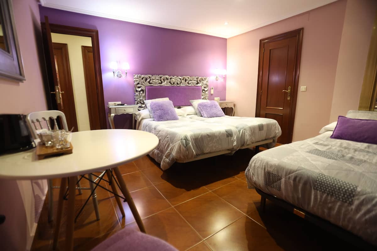 Ein Hotelzimmer mit zwei Betten, einem Esstisch und einer kleinen Küchenzeile.
