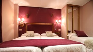 A hotel room with two beds, a large mirror, and wall sconces. - Hostal Goya Suites (Salamanca)