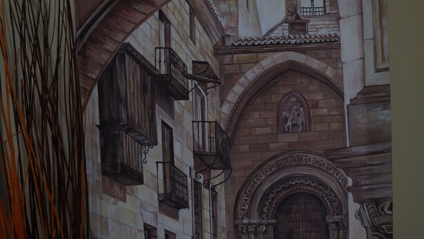 A detailed architectural drawing of a building with a stone facade, arched doorways, and a staircase leading to an upper level. - Hostal Goya Suites (Salamanca)