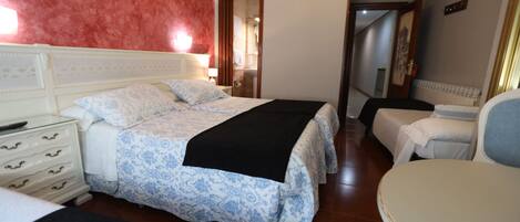 A hotel room with a large bed, a bedside table, a chair, and a wardrobe.
