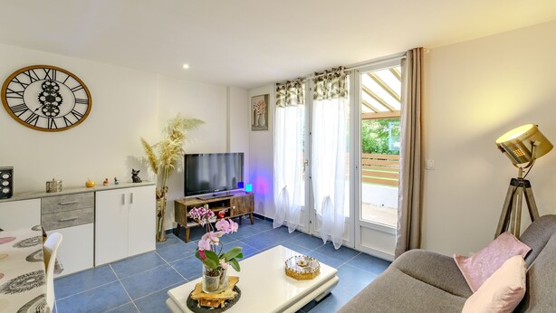 A modern living room with a sofa, coffee table, TV, and decorative plants.