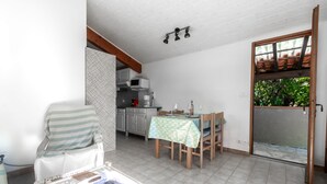 Un coin repas avec une table dressée pour deux personnes, une chaise et une cuisine en arrière-plan.