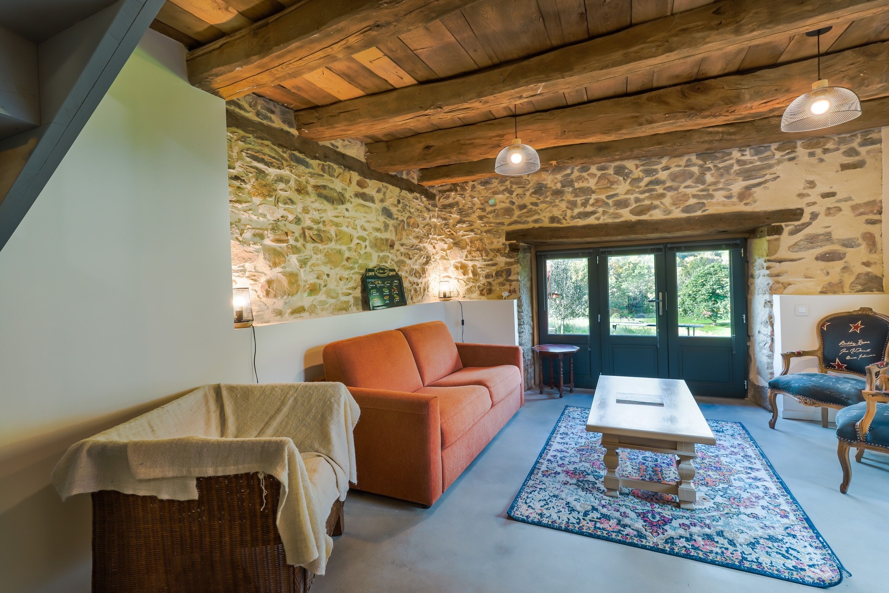 Una habitación acogedora con pared de piedra, techo de madera, un sofá, una mesa y una silla.