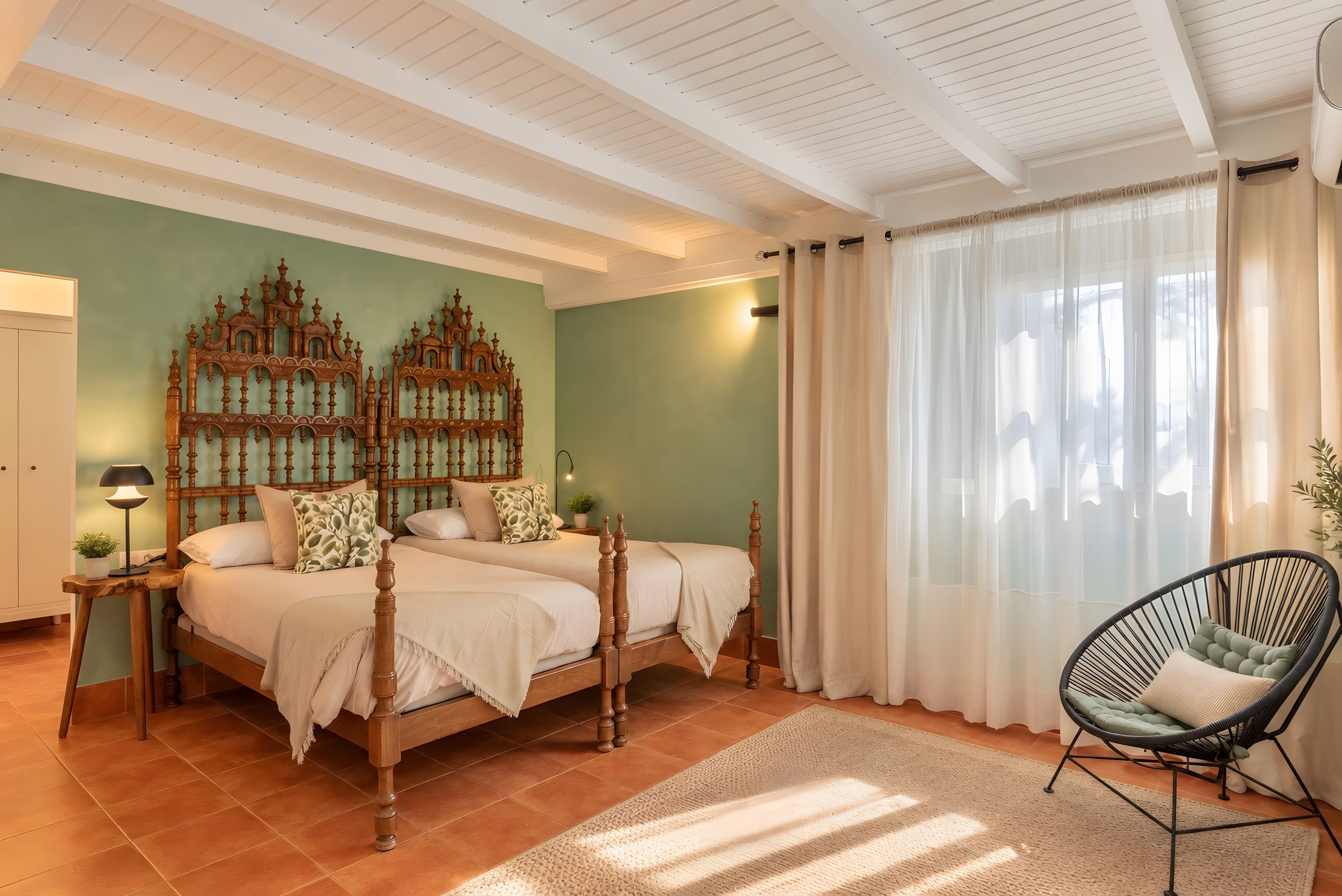 Un dormitorio con una cama grande, dos mesitas de noche, una silla y un panel decorativo en la pared.