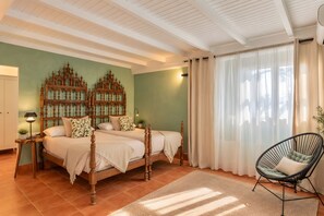 Un dormitorio con una cama grande, dos mesitas de noche, una silla y un panel decorativo en la pared.