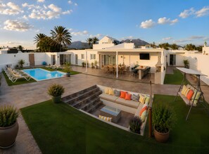 Uma área de estar moderna ao ar livre, com piscina, assentos e um alpendre.