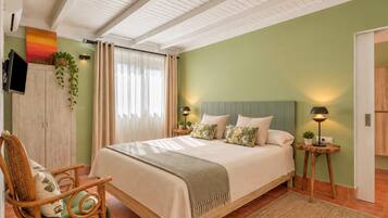 Un dormitorio con cama, una silla, televisión y ventana con cortinas.