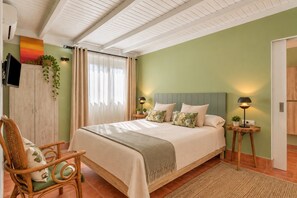 A bedroom with a bed, a chair, a TV, and a window with curtains.