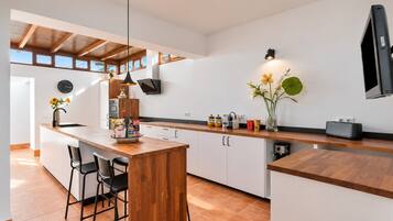 A modern kitchen with a wooden island, bar stools, and a built-in oven.