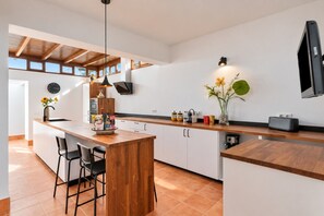 Una cocina moderna con una isla de madera, taburetes de bar y un horno empotrado.