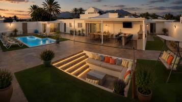 A modern outdoor living space with a pool, seating area, and a patio with a table and chairs.
