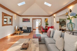 Un vaste espace de vie doté d’un plafond haut, un coin repas et une chambre à coucher visible à travers une porte ouverte.
