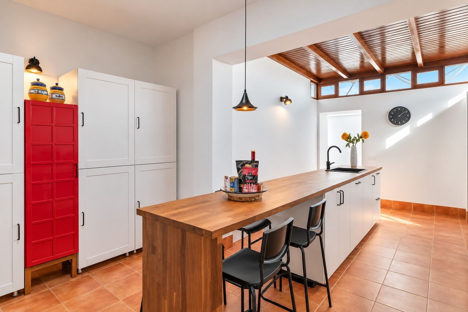 A modern kitchen with a wooden island, red cabinets, and a black faucet.