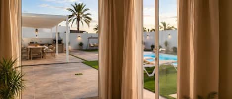 A spacious patio with a pool, dining area, and a view of the outdoors.