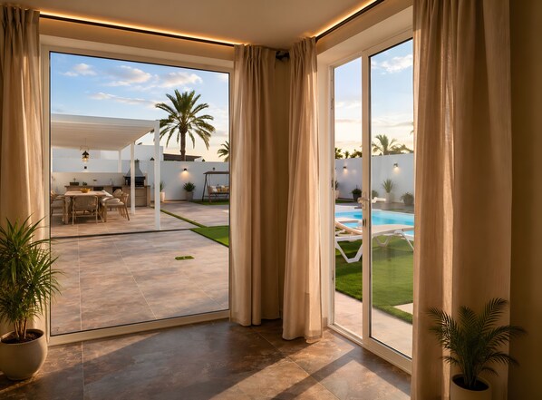 Um pátio amplo com piscina, área de refeições e vista para o exterior.