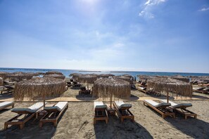A beach with wooden lounge chairs and straw umbrellas. - Berengaria Court - Sea Views 2bdr Apartment (Limassol)
