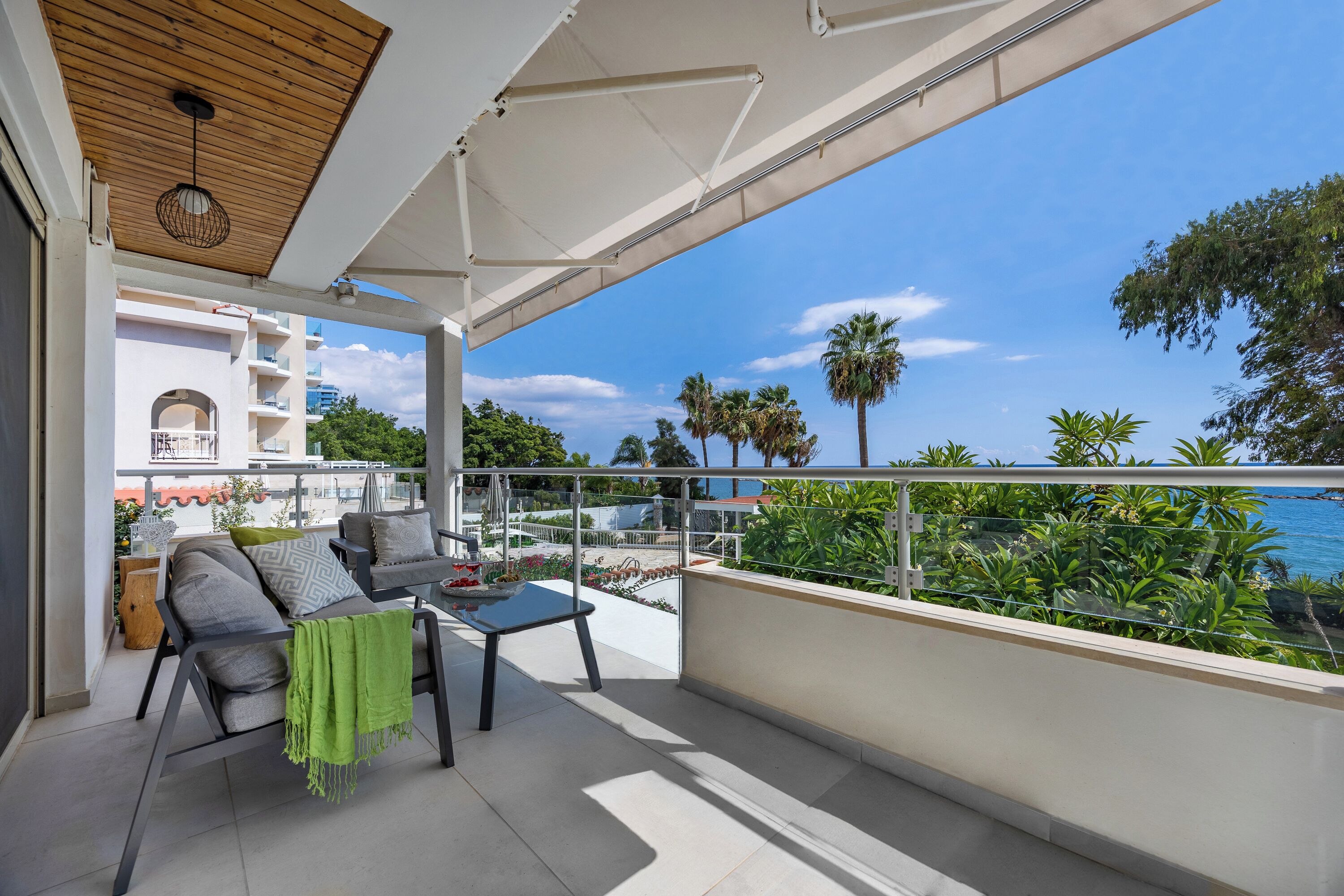 A balcony with a view of the sea, a sofa, and a table.
