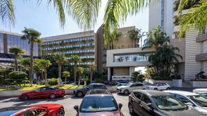 A parking lot with multiple cars, palm trees, and modern buildings with balconies. - Berengaria Court - Sea Views 2bdr Apartment (Limassol)