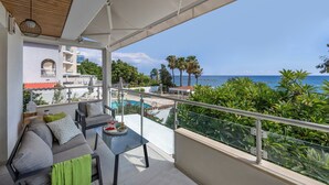 A balcony with a sofa, table, and a view of the sea and greenery. - Berengaria Court - Sea Views 2bdr Apartment (Limassol)