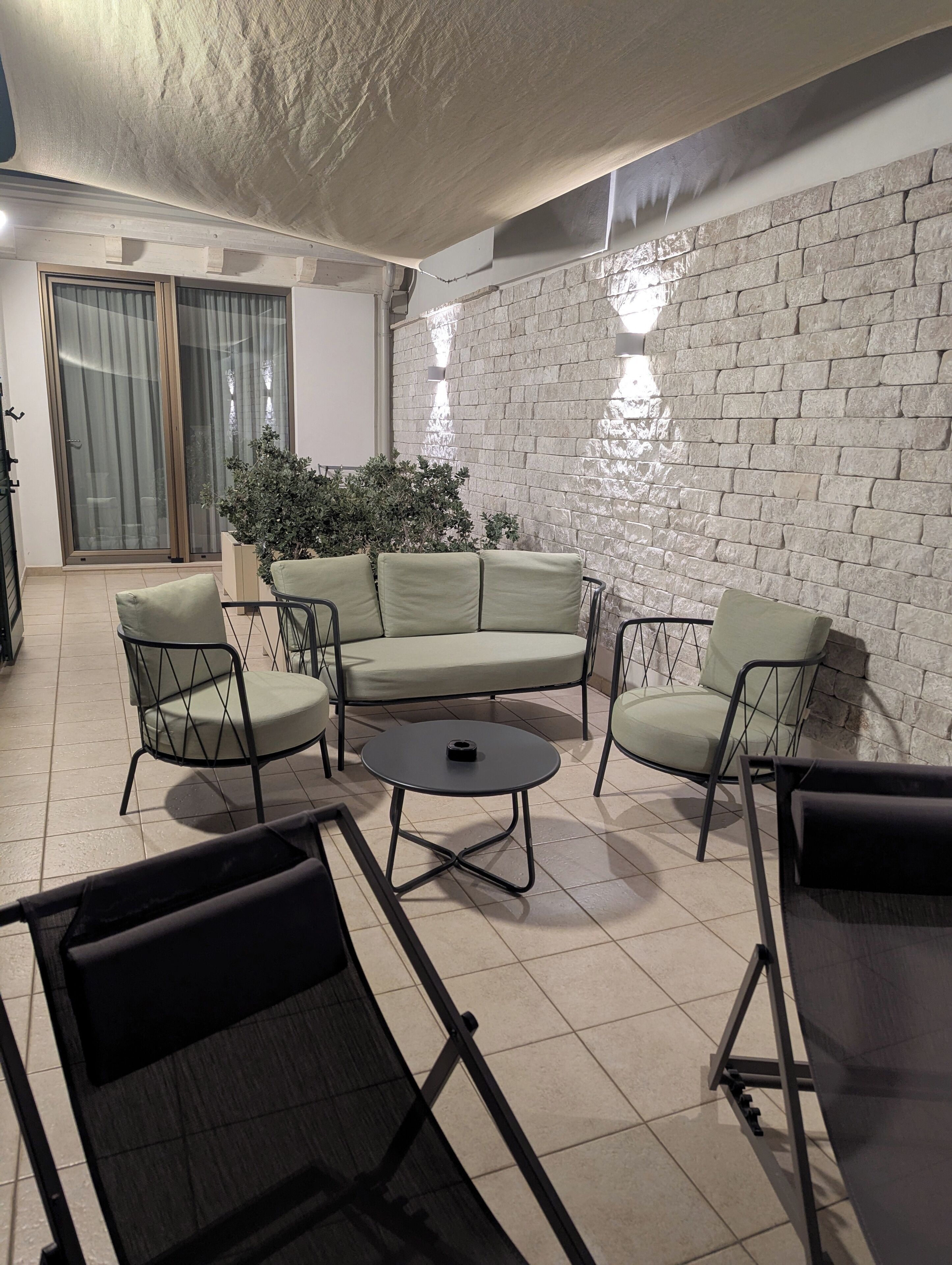 A living area with a stone wall, a green sofa set, a round coffee table, and a glass partition.