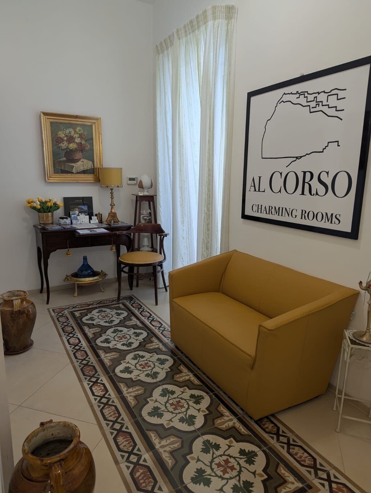 A living room with a sofa, a desk with a lamp, a framed picture, and a rug.