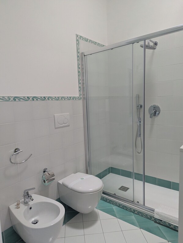 Un baño con ducha de vidrio, lavamanos e inodoro.