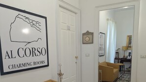 A living room with a tan sofa, a patterned rug, a large mirror reflecting the room, and a framed sign on the wall.