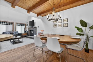 Een moderne woonkamer met een open haard, een eettafel en stoelen.