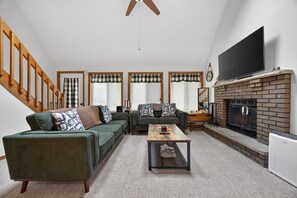 Een woonkamer met een bank, een salontafel, een open haard en een tv erboven.