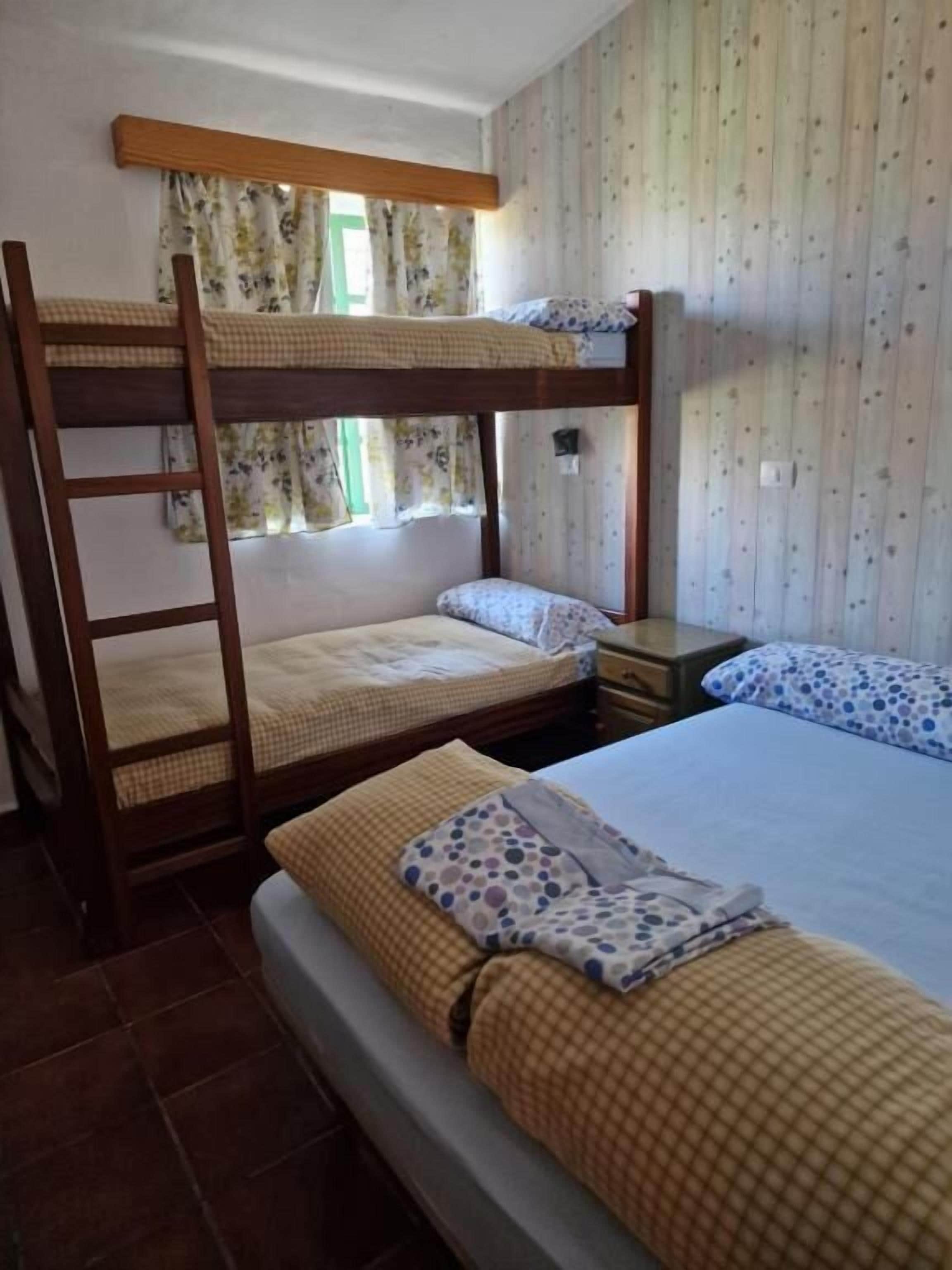 Habitación con literas, dos mesitas de noche y cortinas con estampado floral.