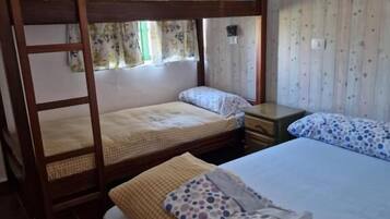 Habitación con literas, dos mesitas de noche y cortinas con estampado floral.