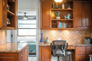 Une cuisine avec des meubles de rangement en bois, un plan de travail et une chaise.