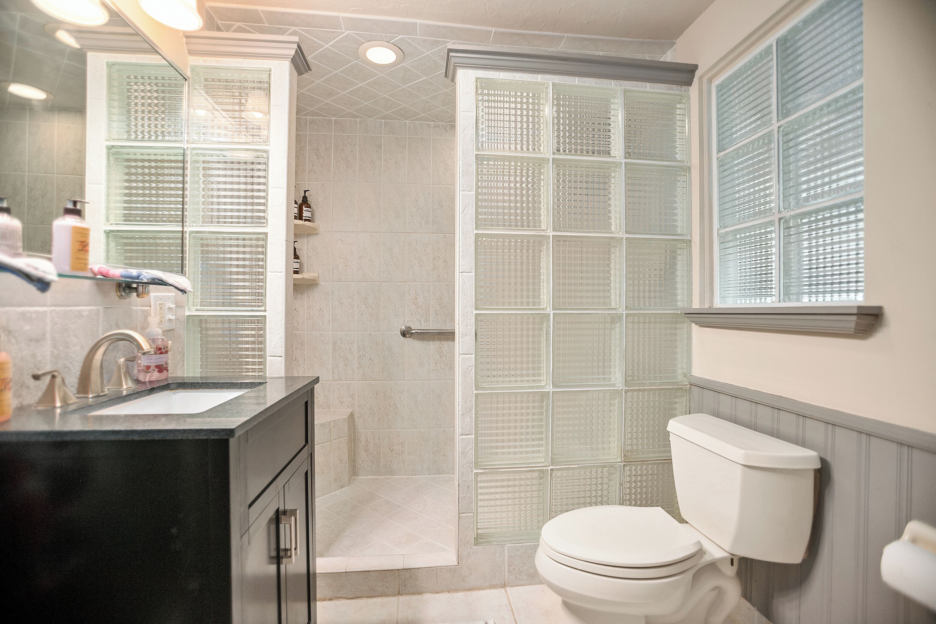 A bathroom with a glass shower enclosure, a white toilet, and a black vanity with a sink.