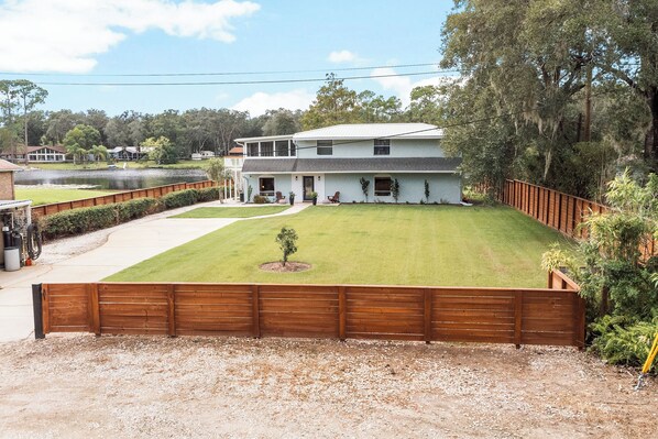 Une maison à deux étages avec une pelouse bien entretenue et une clôture en bois.