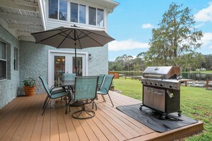 Une terrasse avec une table et des chaises, un barbecue et une vue sur un lac.