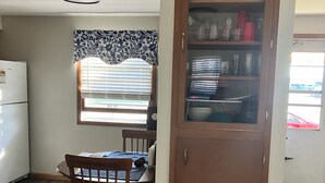 A compact kitchen with a dining area, a built-in cabinet, and a window with blinds.