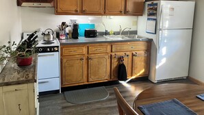 A kitchen with wooden cabinets, a white refrigerator, a stove, and a sink.